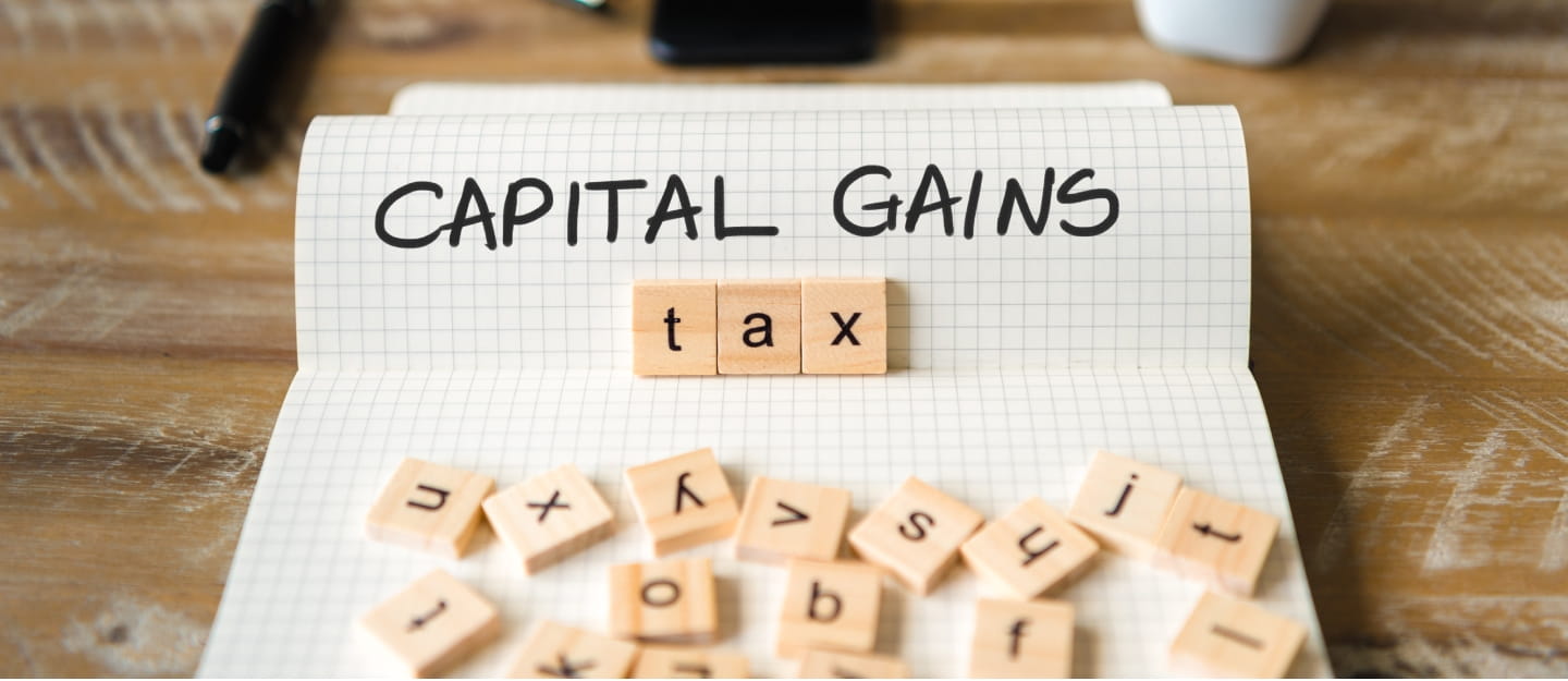 The words 'Capital Gains' on paper and the word 'tax' on scramble pieces