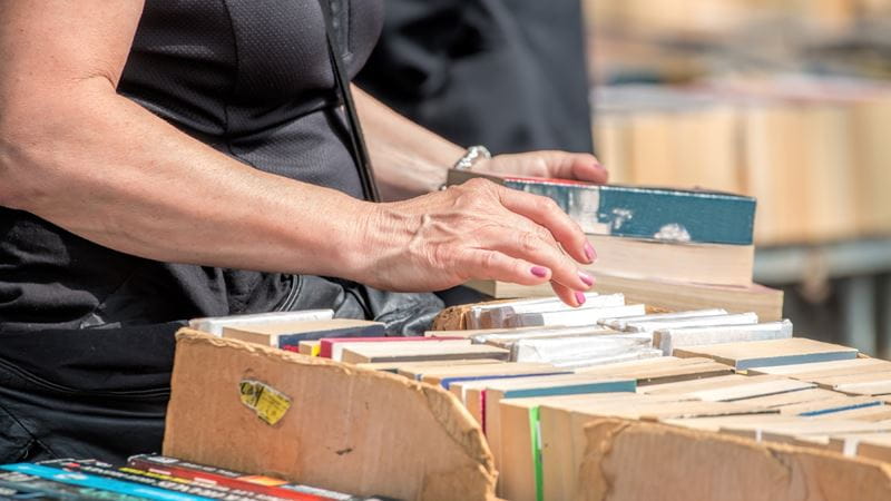 A woman sifting through a box of second hand books