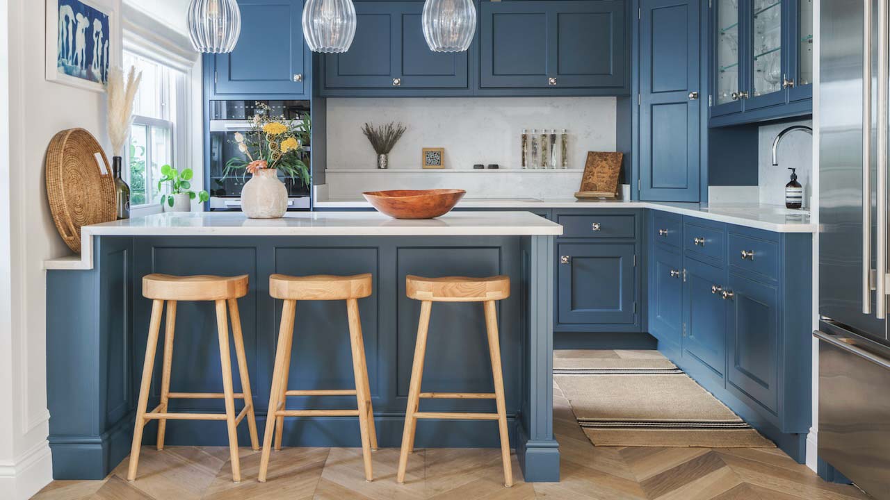 Three barstools at a breakfast bar in a white and navy kitchen