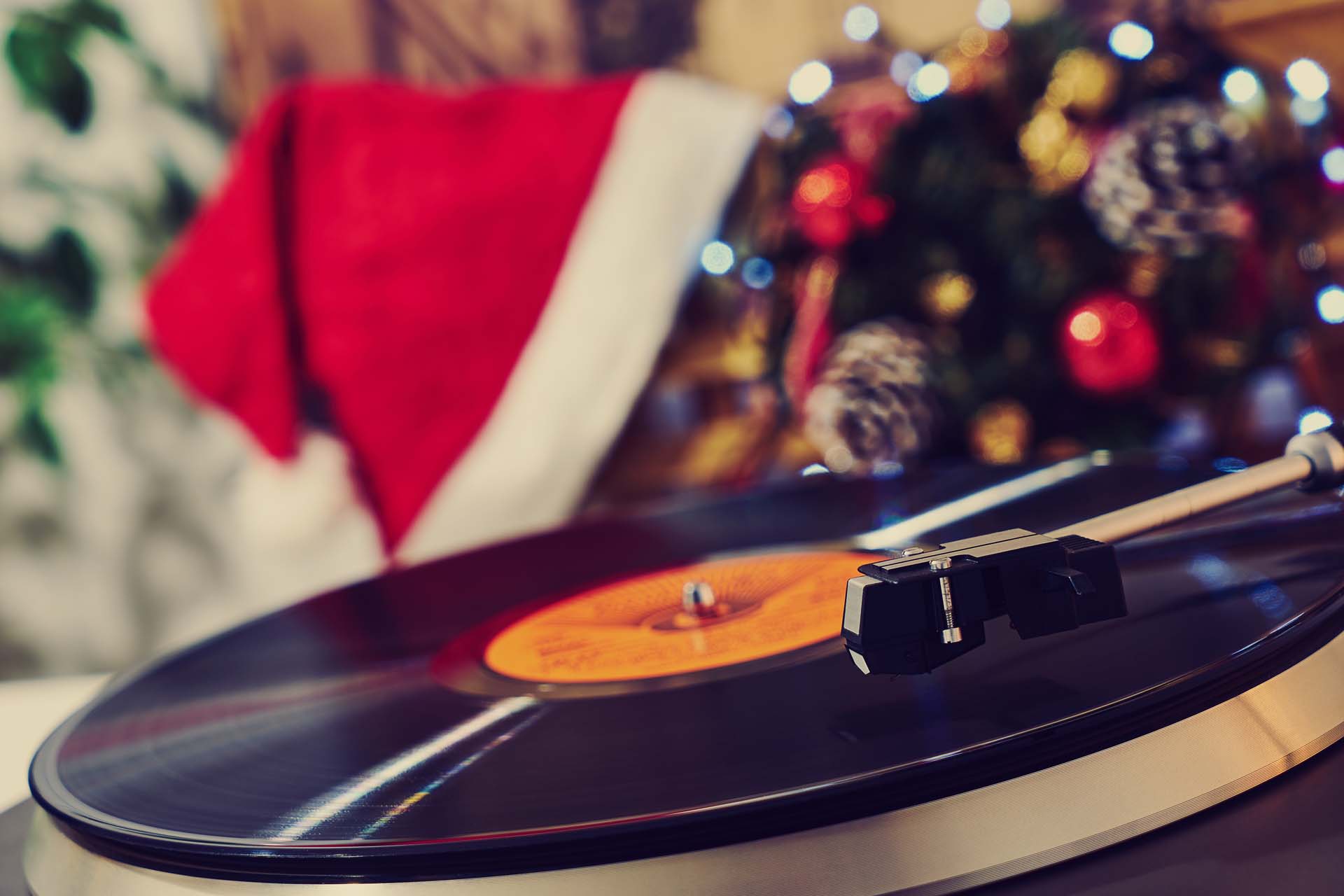 Close-up of a record playing with a Father Christmas hat and Christmas decorations in the background