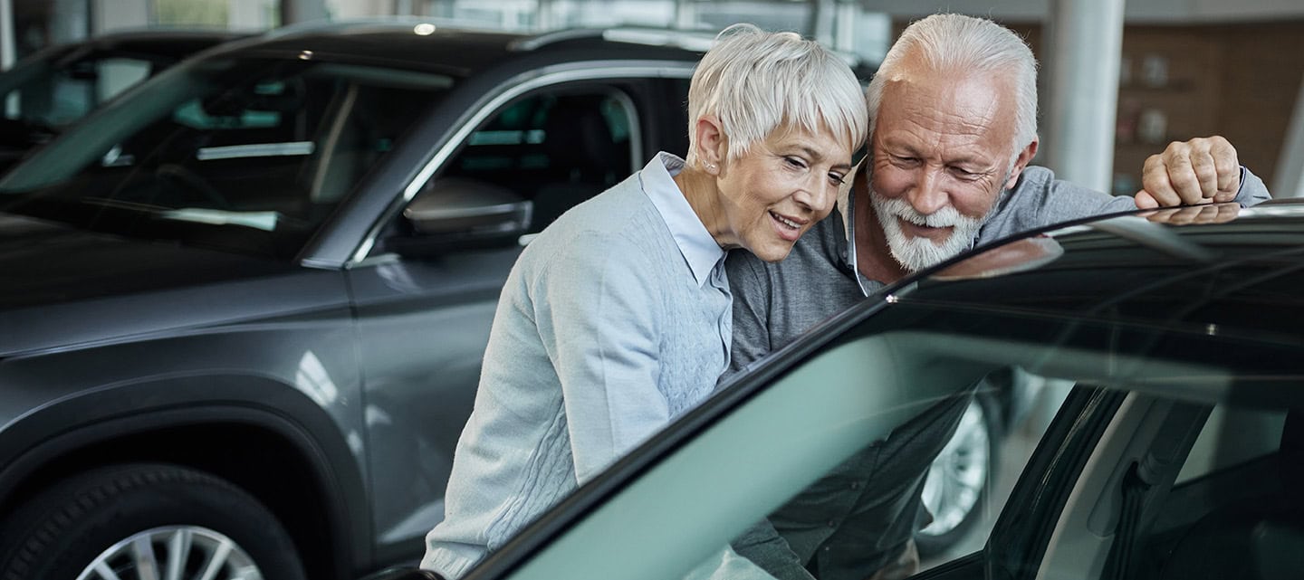 Happy mature couple searching for the right car in a showroom.