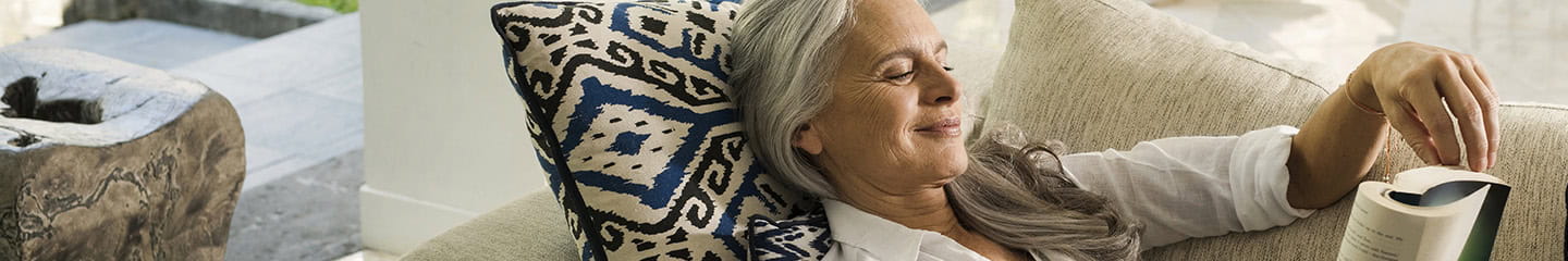 Elegant senior woman relaxing on couch, reading a book