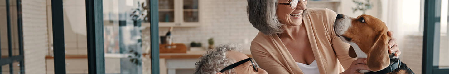 A senior couple laughing with their pet dog at home