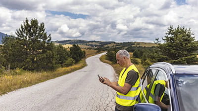 Frustrated mature man calling roadside assistance after breaking down.