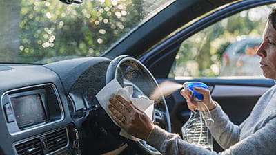 Woman wiping down car steering wheel 