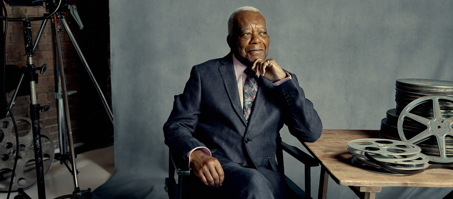 sir trevor mcdonald sat on chair by a table looking thoughtful