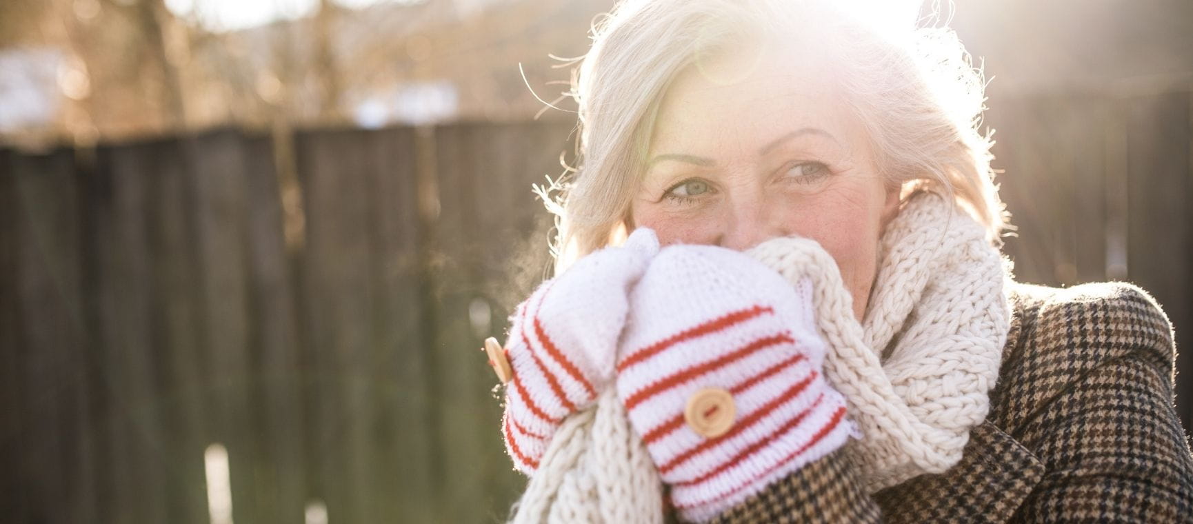 A woman wrapped up in gloves and scarf on a sunny winter day