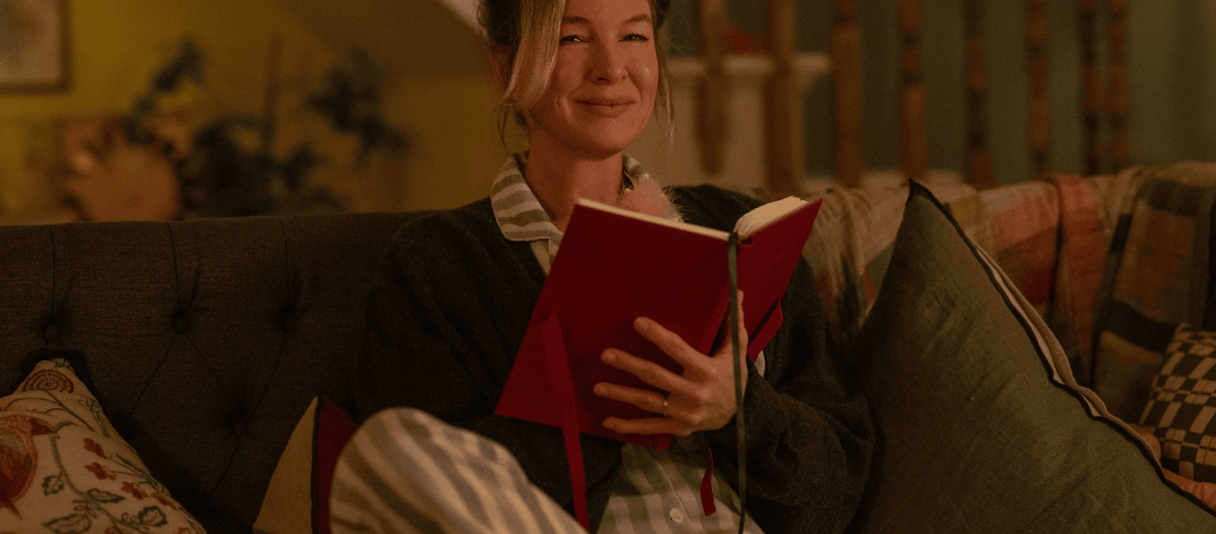 Character Bridget Jones holding her diary on a sofa