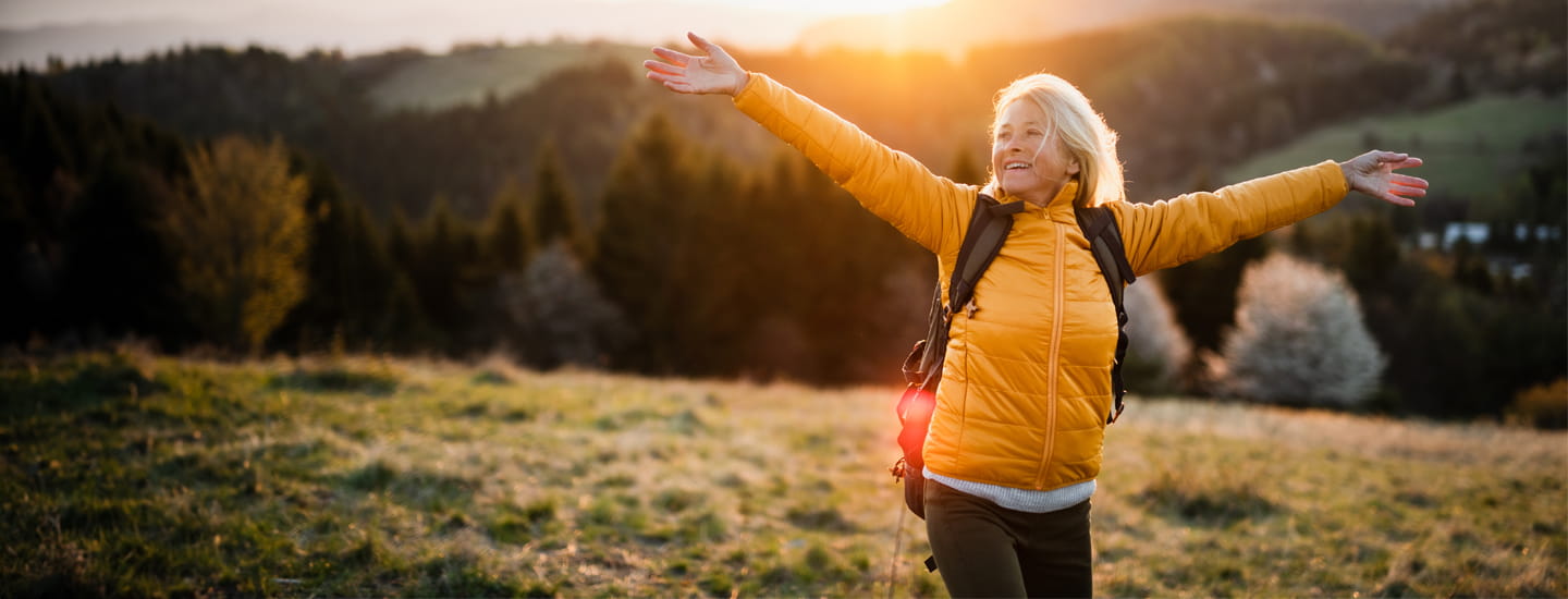 A woman with her arms open wide on a hillside