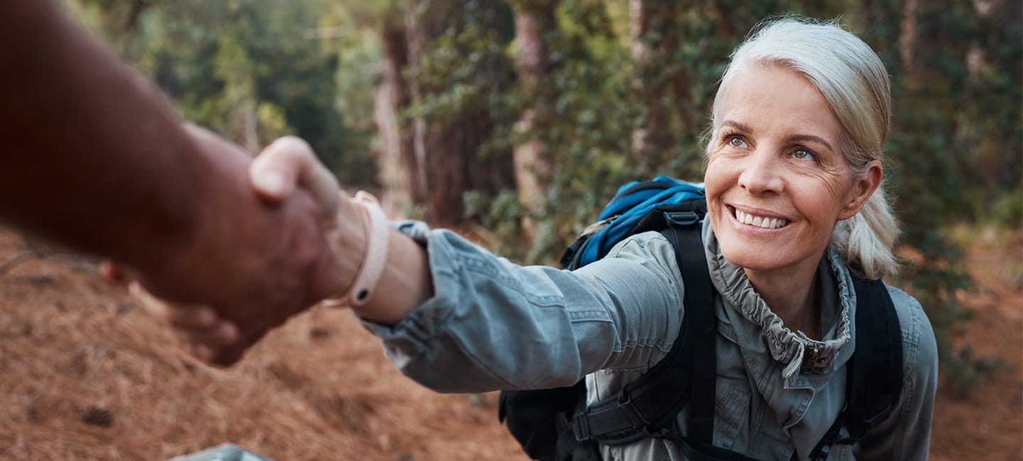 A lady taking an offered helping hand while out hiking