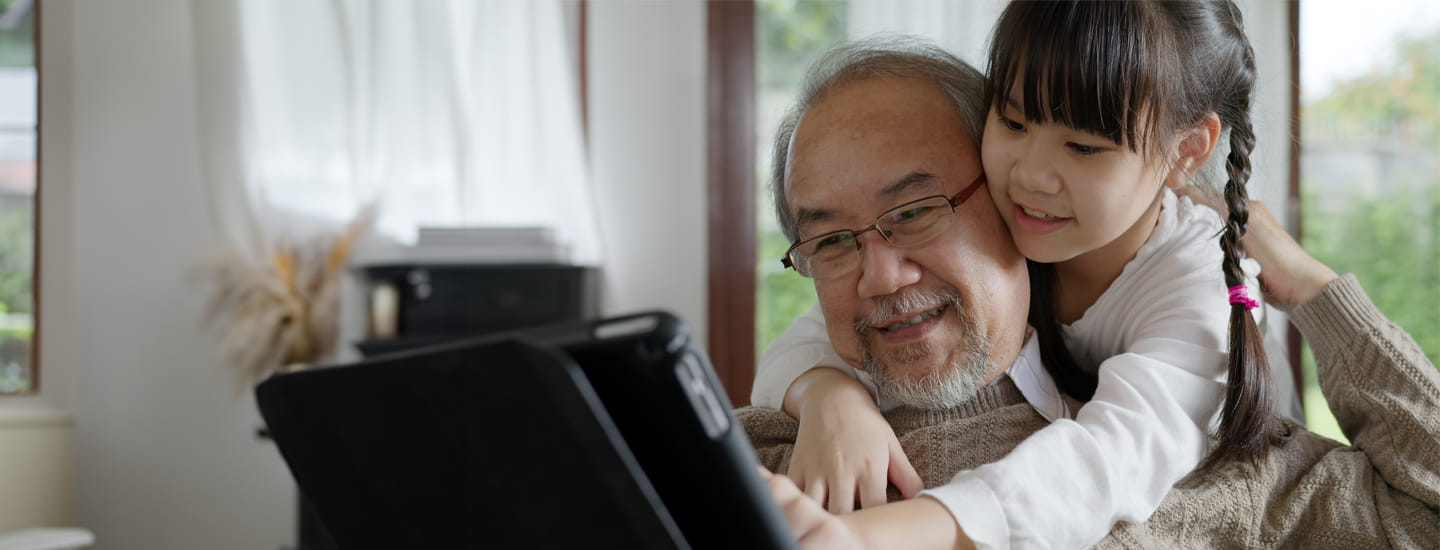 A grandfather looking at a book with his granddaughter