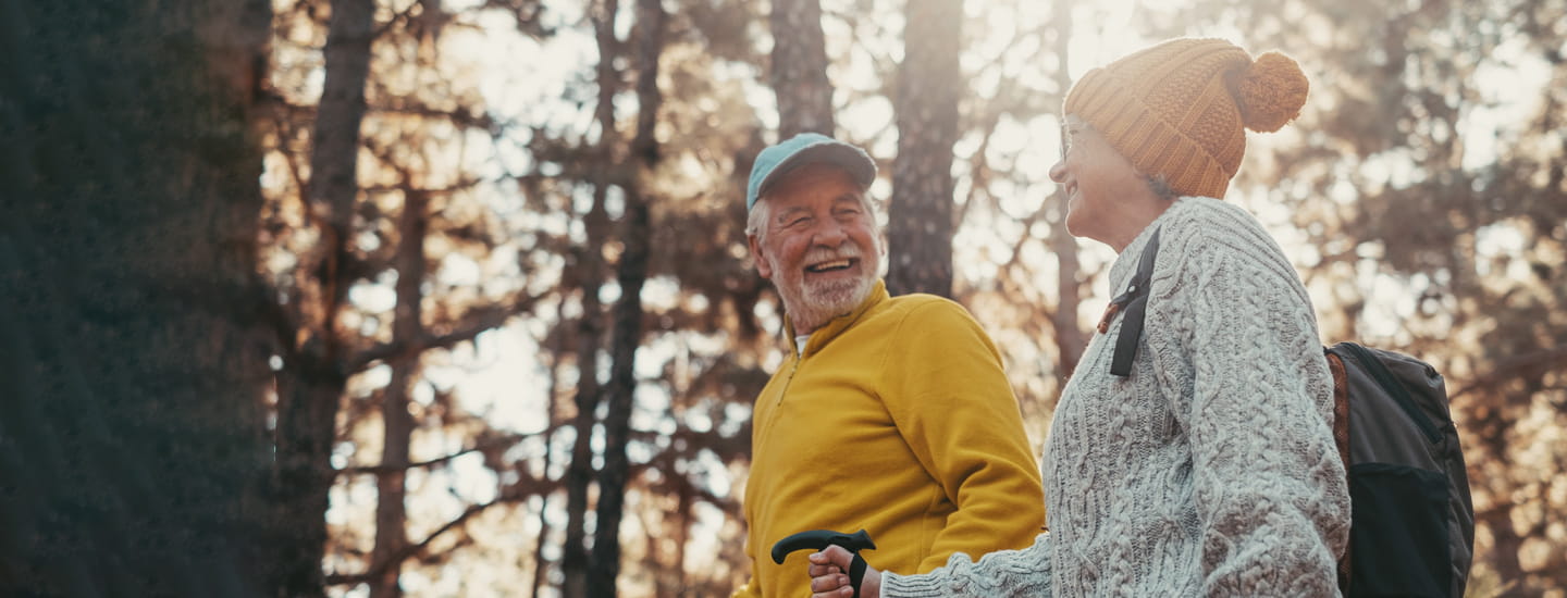 A mature couple walking and smiling through woodland