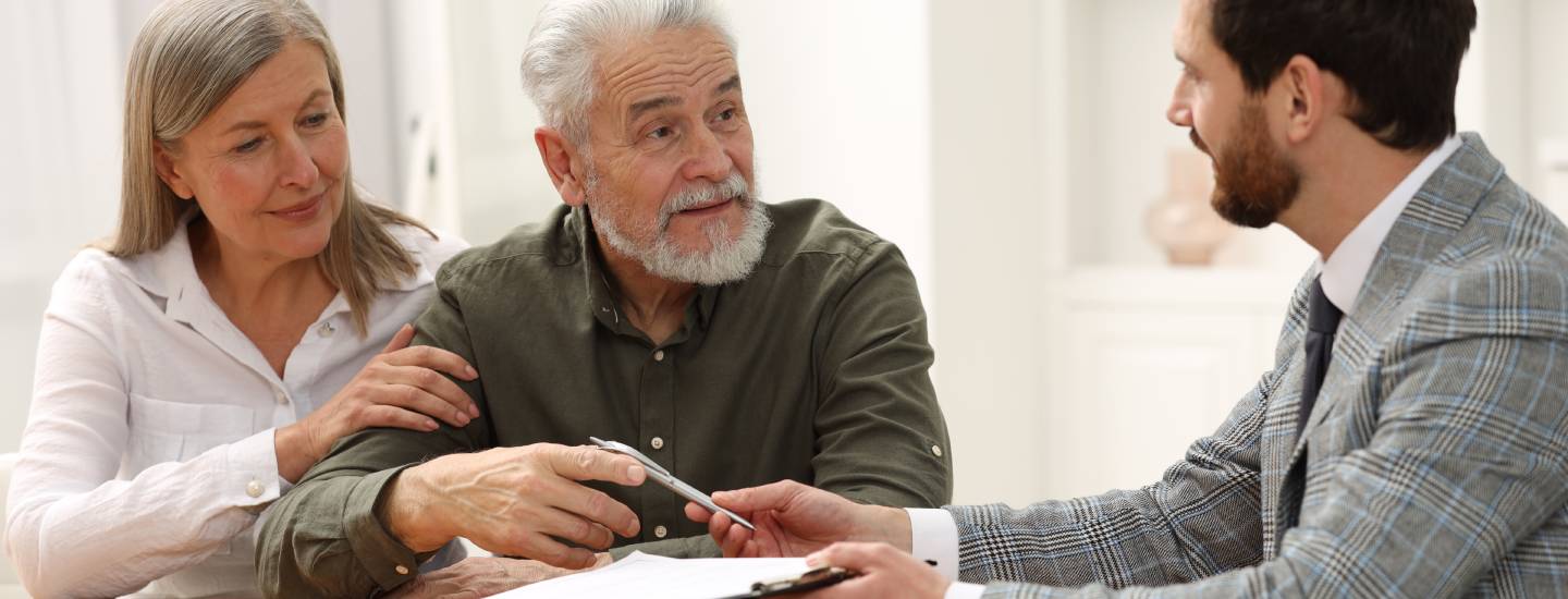 Mature copy sitting with a lawyer about to sign a legal document 