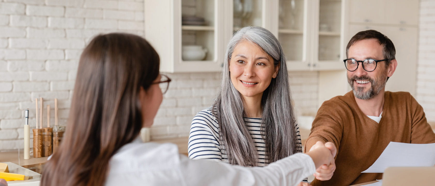 Happy mature middle-aged couple clients signing documents