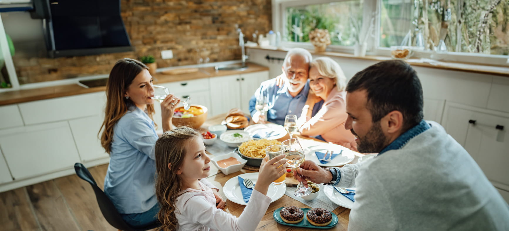 A family including grandparents sat having a meal smiling and happy