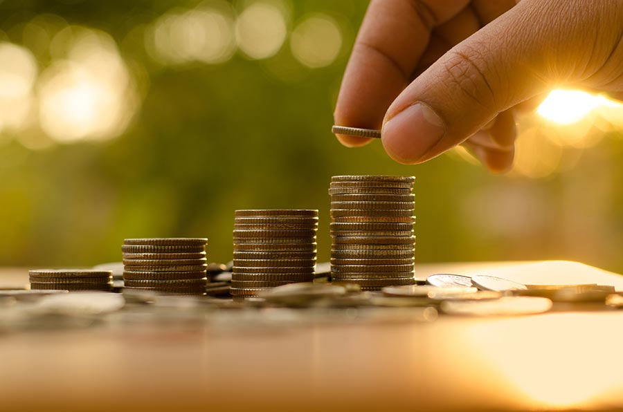 A hand placing a coin onto a pile of coins