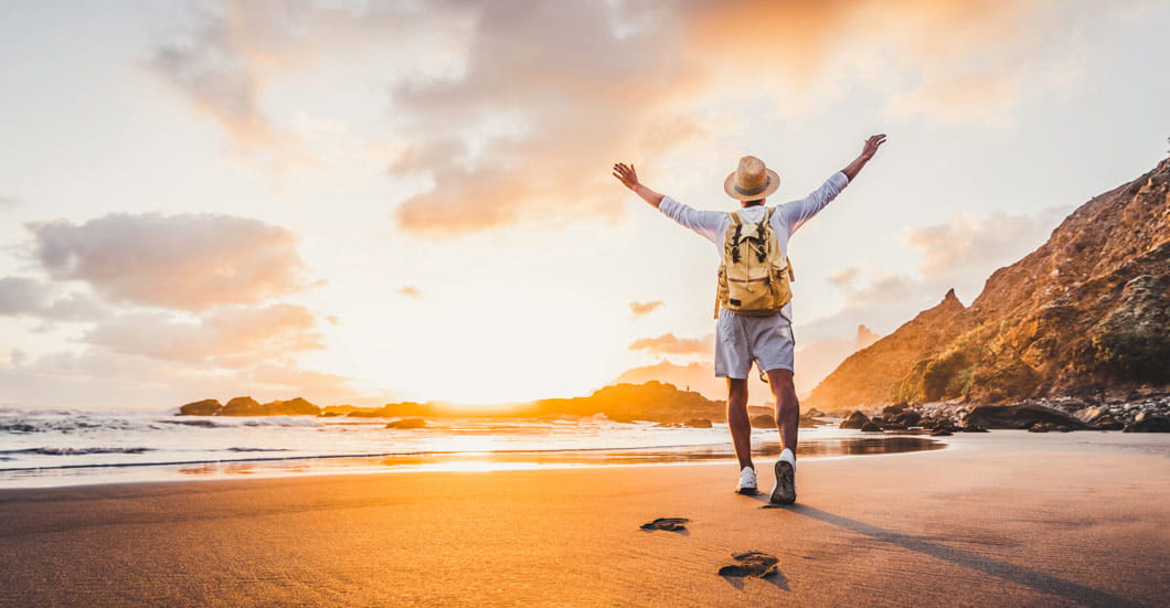 A man on a beach looking out to sea as the sun rises